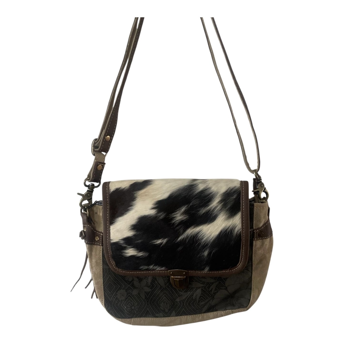 A shoulder bag with a black and white cowhide pattern on the front flap, dark brown leather trim, and a dark brown embossed pattern on the lower front panel, featuring a brown leather strap and a small gold-tone clasp.