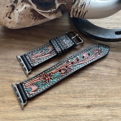 Decorative leather watch strap with intricate designs on a wooden surface.