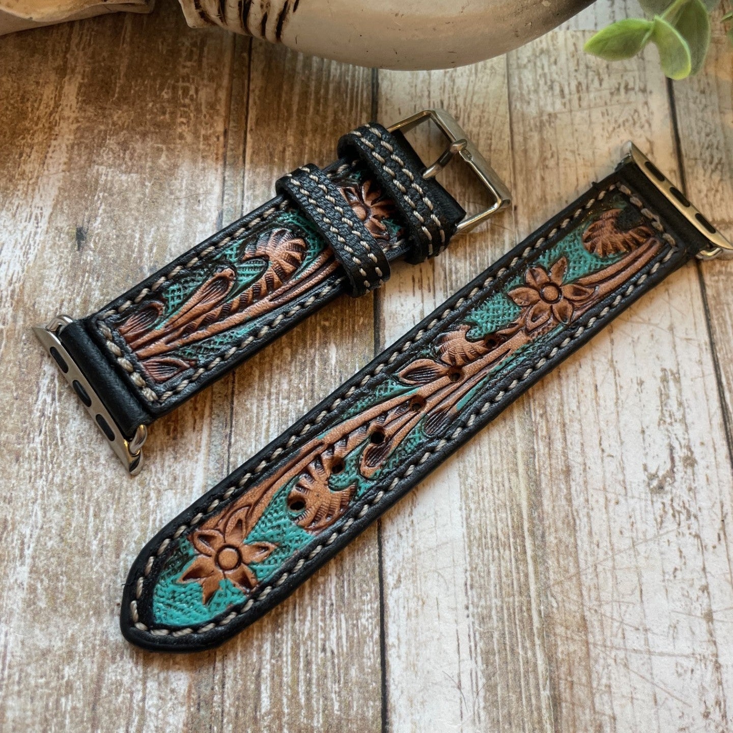 Decorative leather watch strap with intricate patterns on a wooden surface