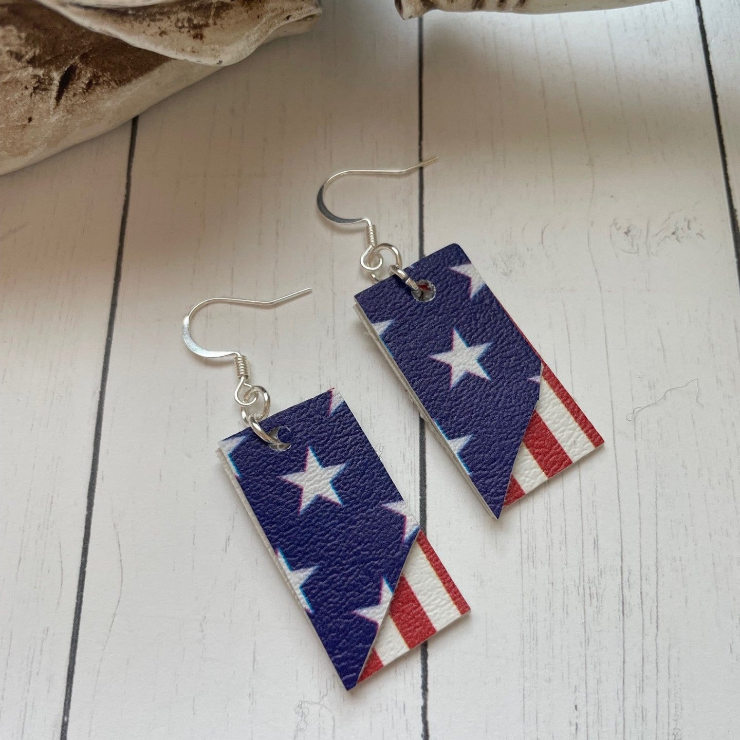 Pair of earrings with American flag design on a wooden surface