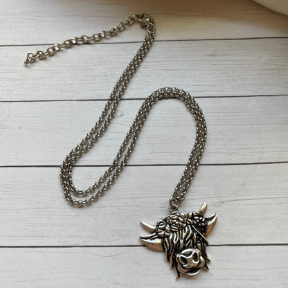 Silver necklace with a detailed pendant on a wooden surface