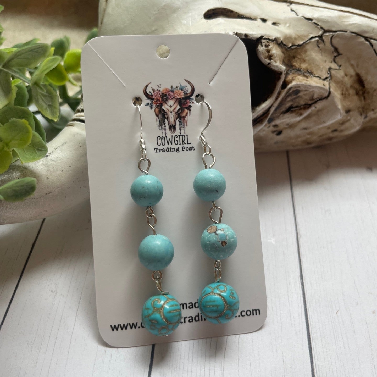 Trio of Turquoise Colored Round Bead Earrings on a white cowgirl trading post display card with a cow bull skull and greenery in the background