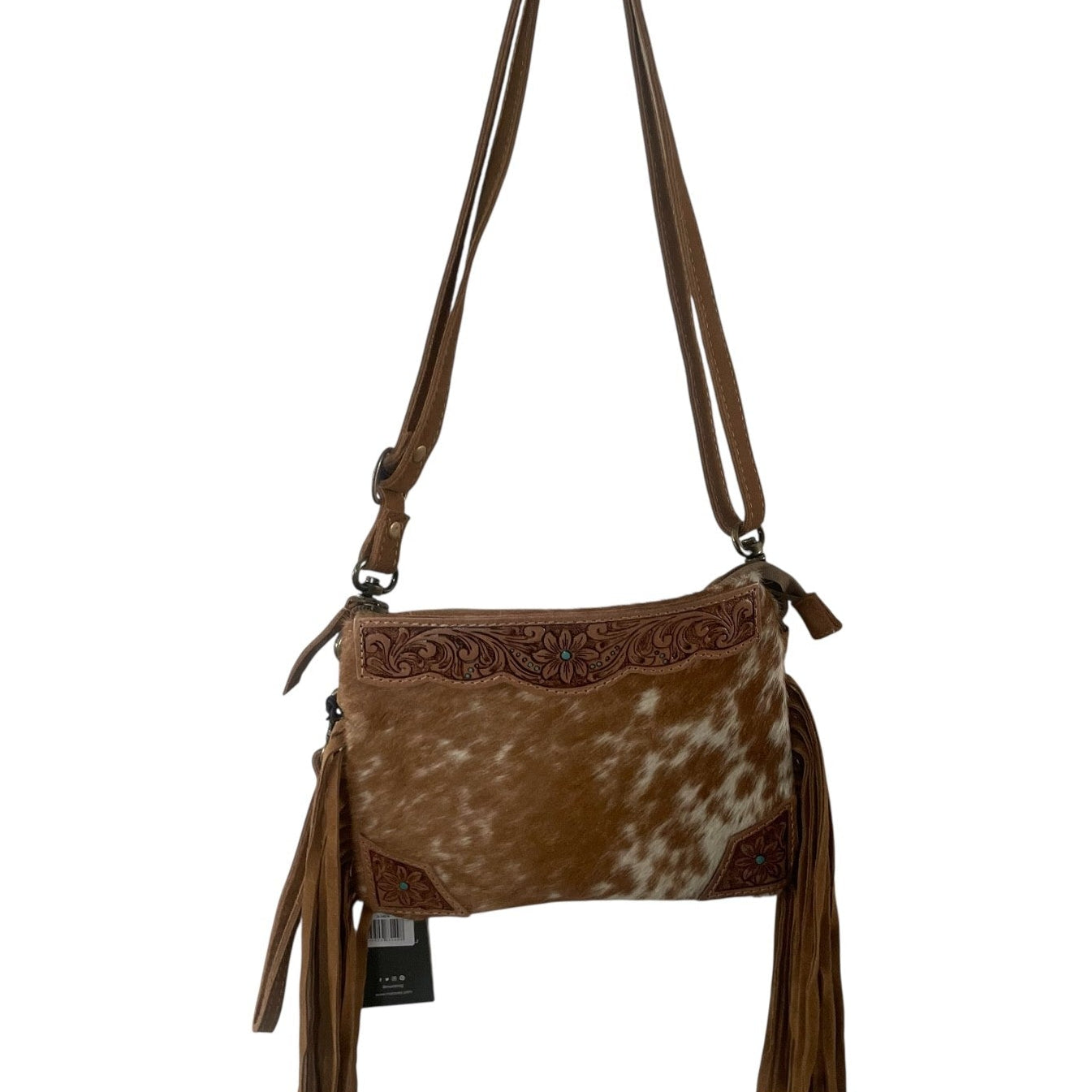 A brown faux-hide and leather crossbody bag with a cowhide-look front panel, tooled leather trim, and long brown fringe tassels, shown against a plain white background.