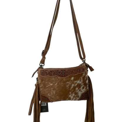 A brown faux-hide and leather crossbody bag with a cowhide-look front panel, tooled leather trim, and long brown fringe tassels, shown against a plain white background.