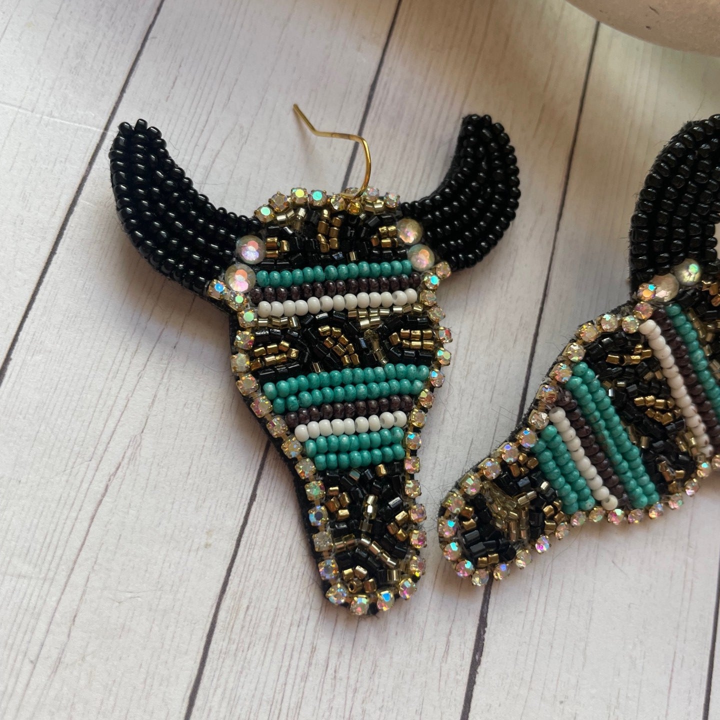 Beaded bull cow-shaped earrings on a wooden surface