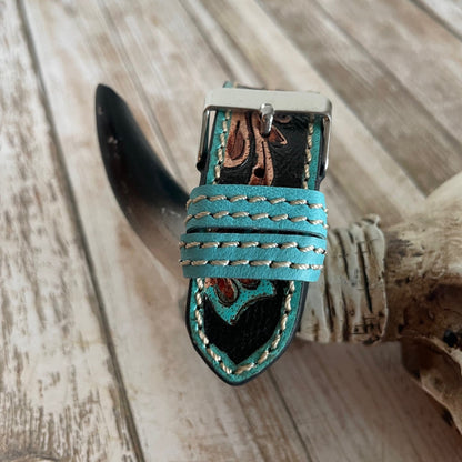 Teal leather strap with decorative buckle on a wooden surface