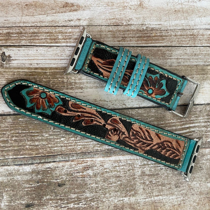 Two leather watch straps with floral patterns on a wooden surface