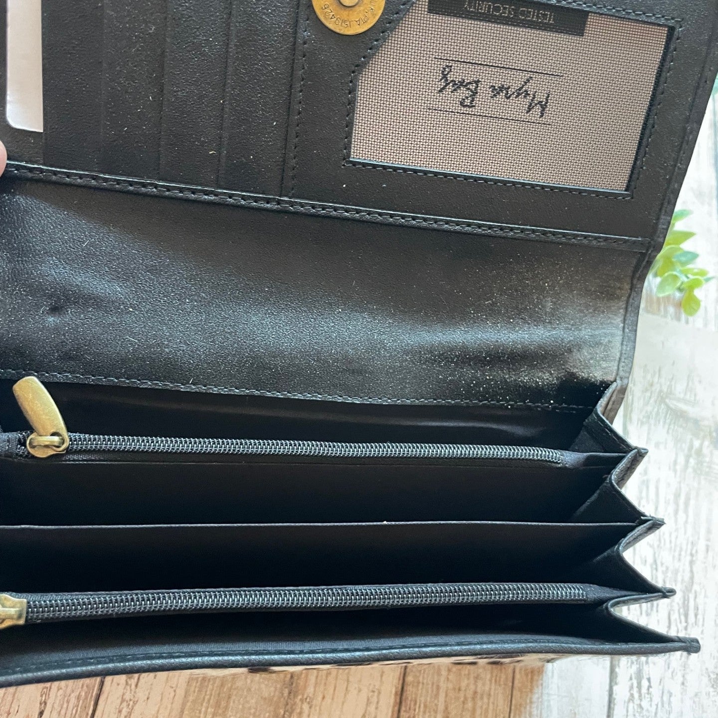 Black leather wallet with gold accents on a wooden surface