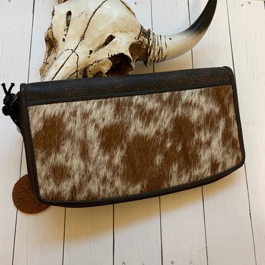Cowhide leather clutch bag on a wooden surface with a skull and horns in the background