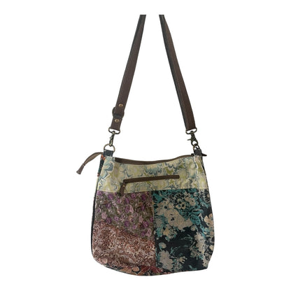 Floral patterned handbag with a strap on a white background