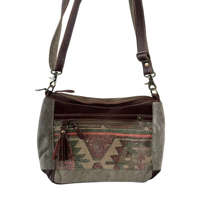 Handbag with patterned flap and shoulder strap on a white background