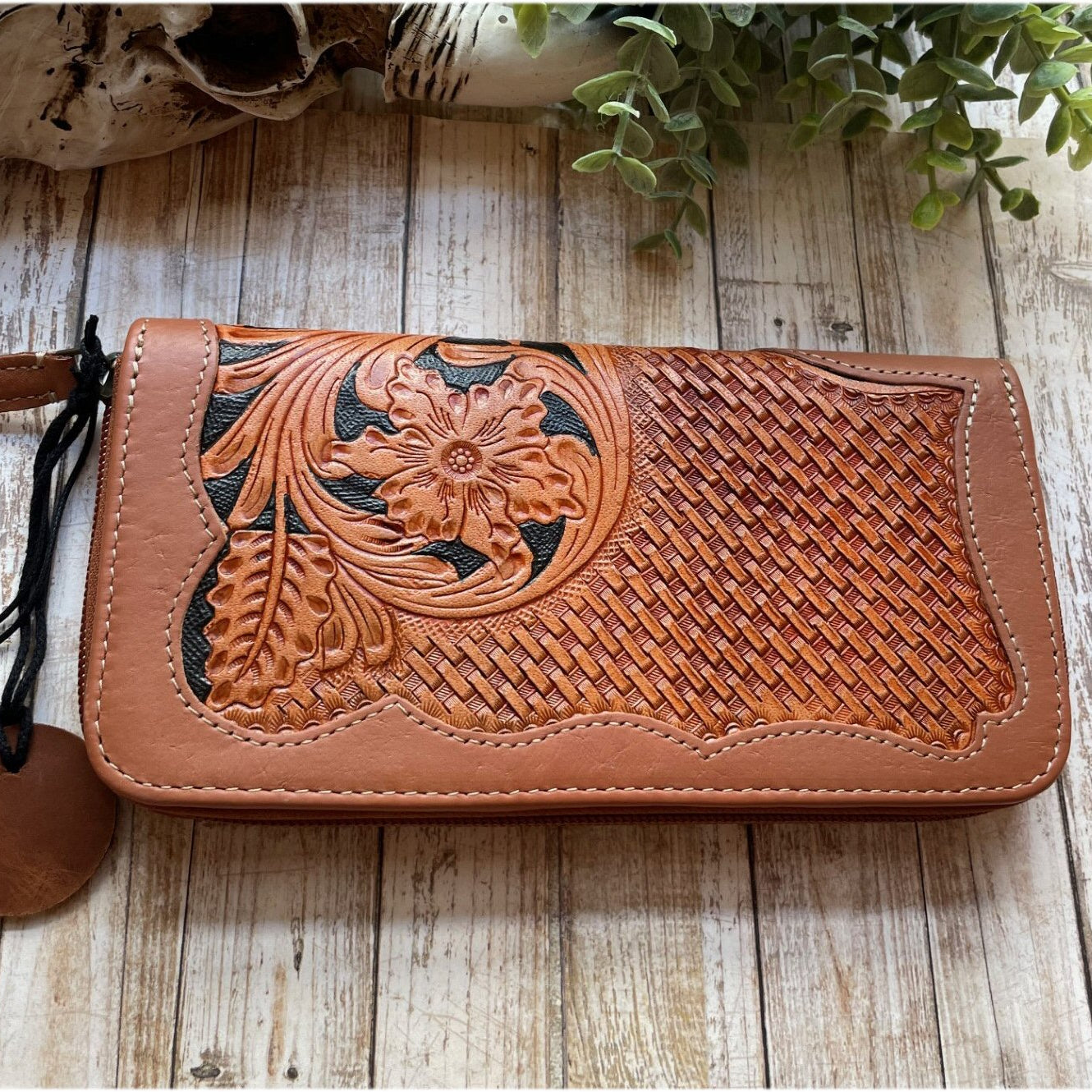 Brown leather wallet with floral embossing on a wooden surface