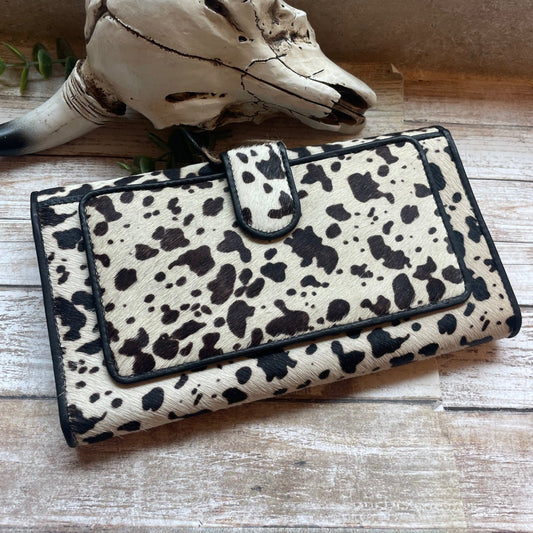 Spotted wallet on a wooden surface with a skull and plant