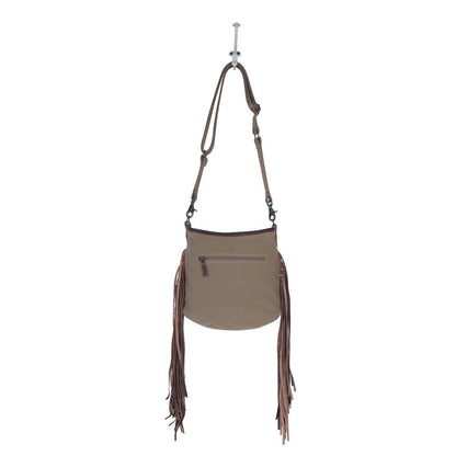 Brown leather handbag with fringe details on a white background
