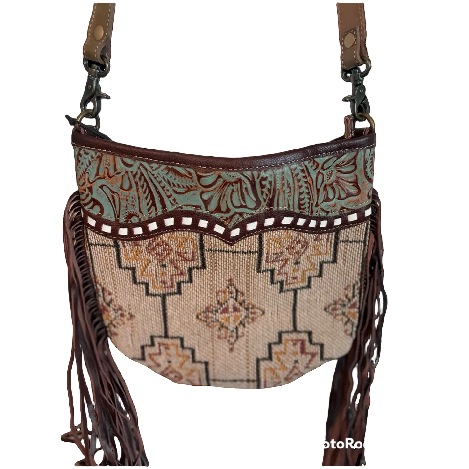 Patterned handbag with fringe and leather accents on a white background