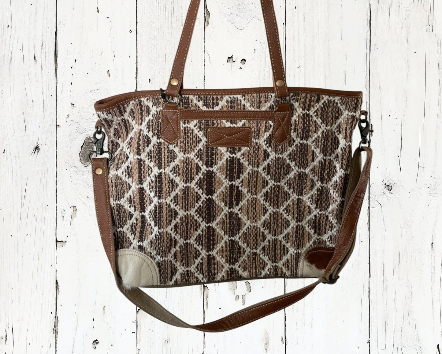 Patterned handbag with brown straps on a white wooden background