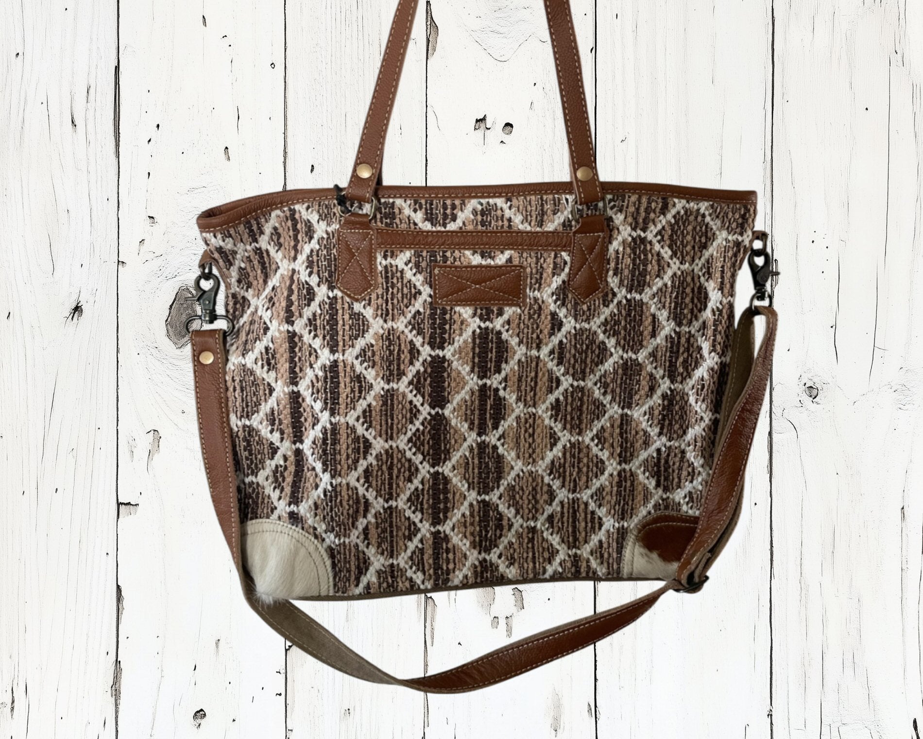 Patterned handbag with brown straps on a white wooden background