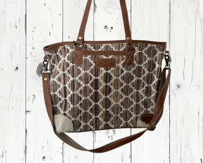 Patterned handbag with brown straps on a white wooden background