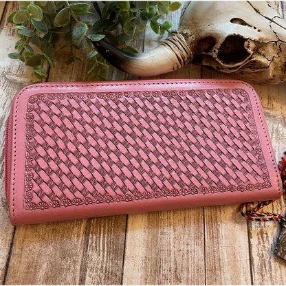 Pink leather wallet with woven pattern on a wooden surface
