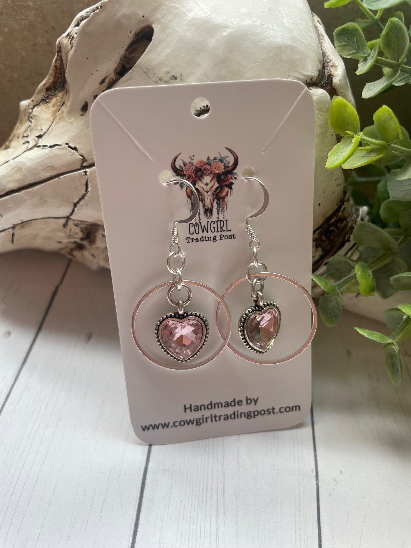Pink sparky hearts with a silver ring around them earrings on a white wood background