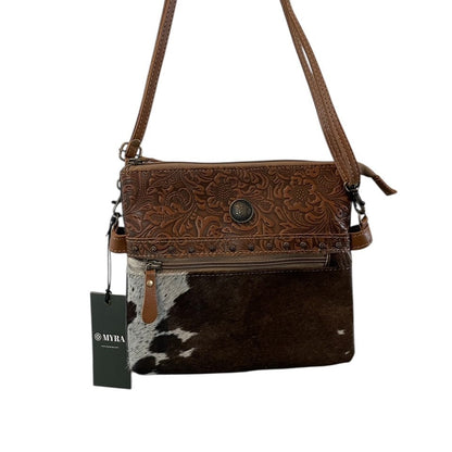 Brown leather handbag with cowhide pattern and a visible tag on a white background
