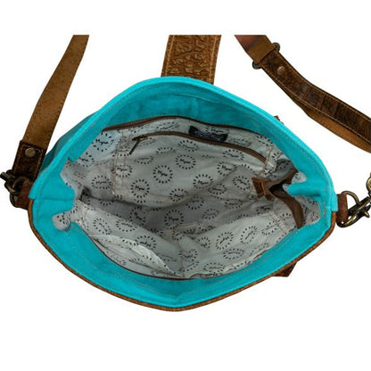 Turquoise handbag with brown strap on a white background