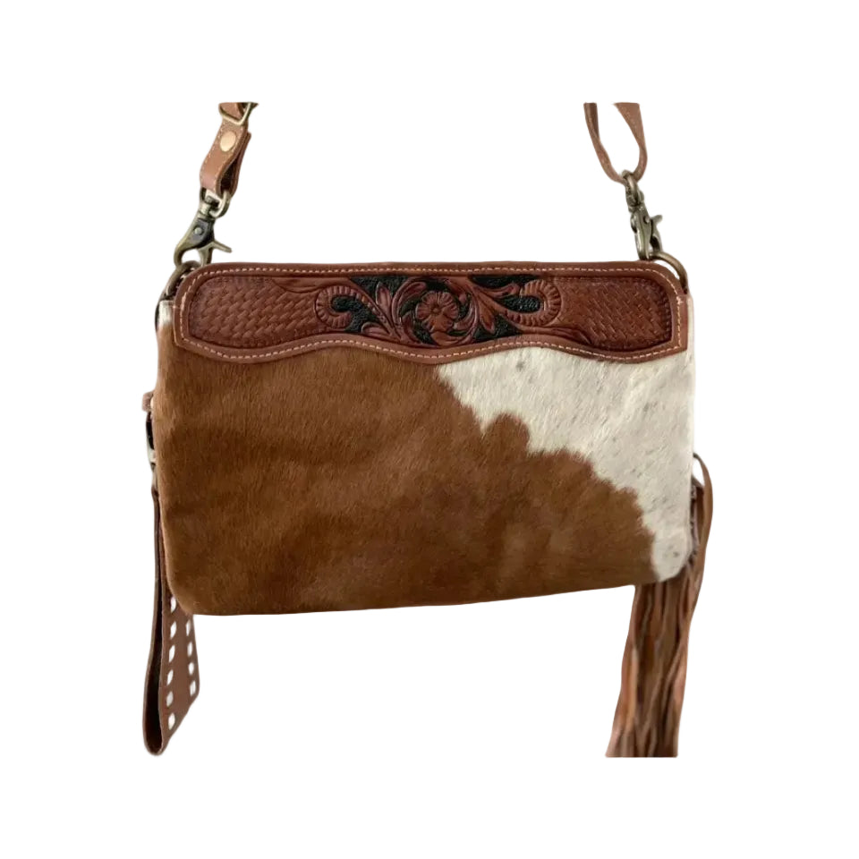 Brown and white cowhide leather handbag with decorative stitching on a white background