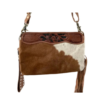 Brown and white cowhide leather handbag with decorative stitching on a white background