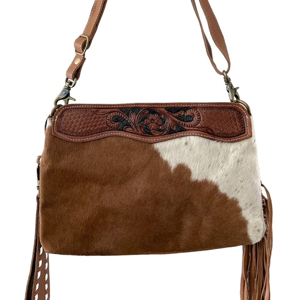 Brown and white cowhide handbag with decorative stitching on a white background