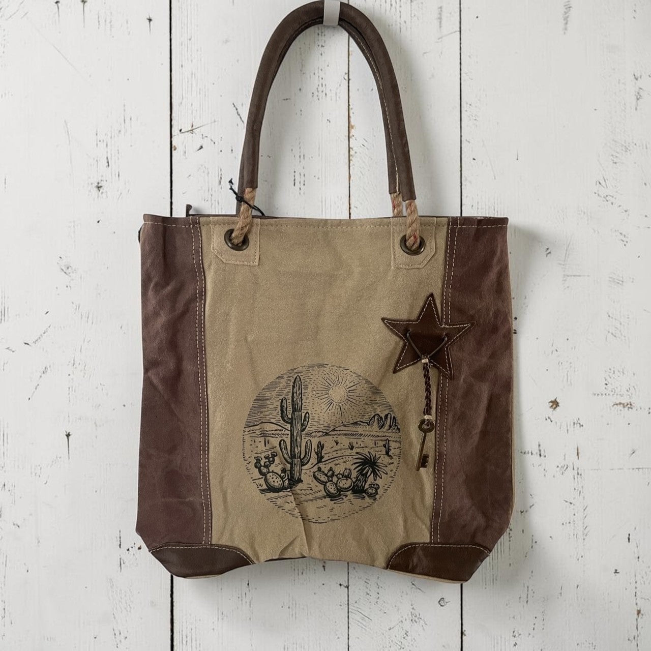 Canvas tote bag with star and desert scene design on a white wooden surface