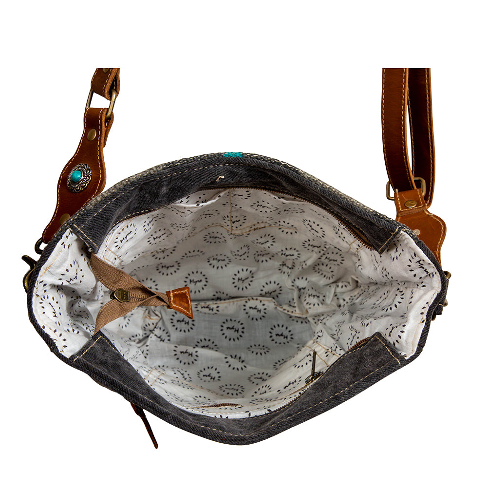Black leather handbag with brown leather straps and turquoise stone on a white background