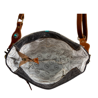 Black leather handbag with brown leather straps and turquoise stone on a white background