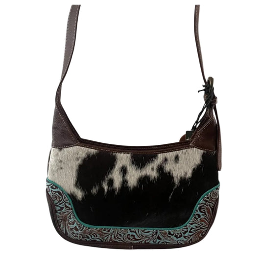 Hobo bag with cowhide pattern and decorative trim on a white background