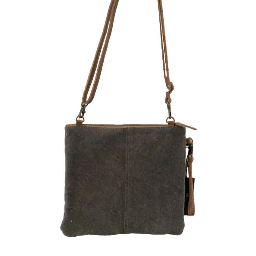 Brown leather crossbody bag with floral design on wooden surface, featuring 'Cowgirl Trading Post' logo.