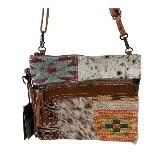 Patchwork rug pattern in brown and orange and cowhide with a leather tassel zipper section