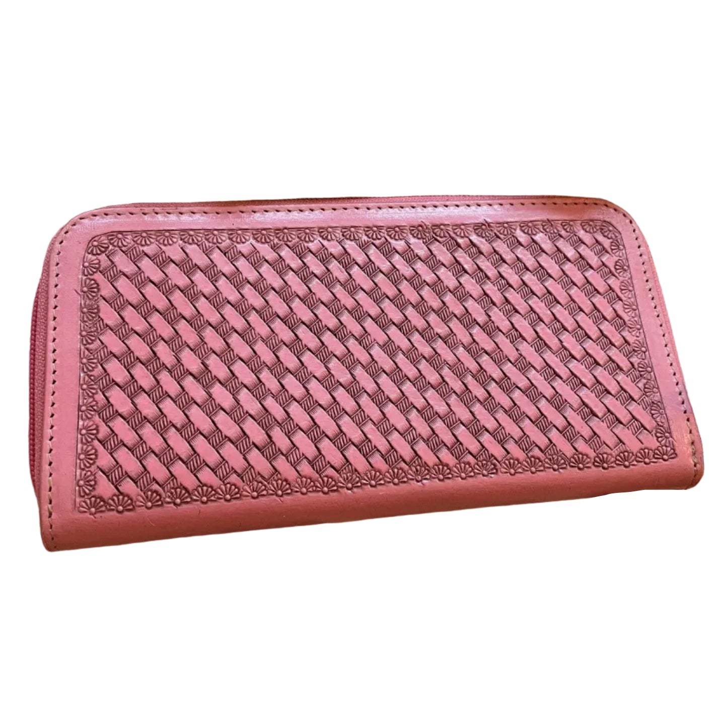 Pink woven wallet on a wooden surface with a plant and skull in the background