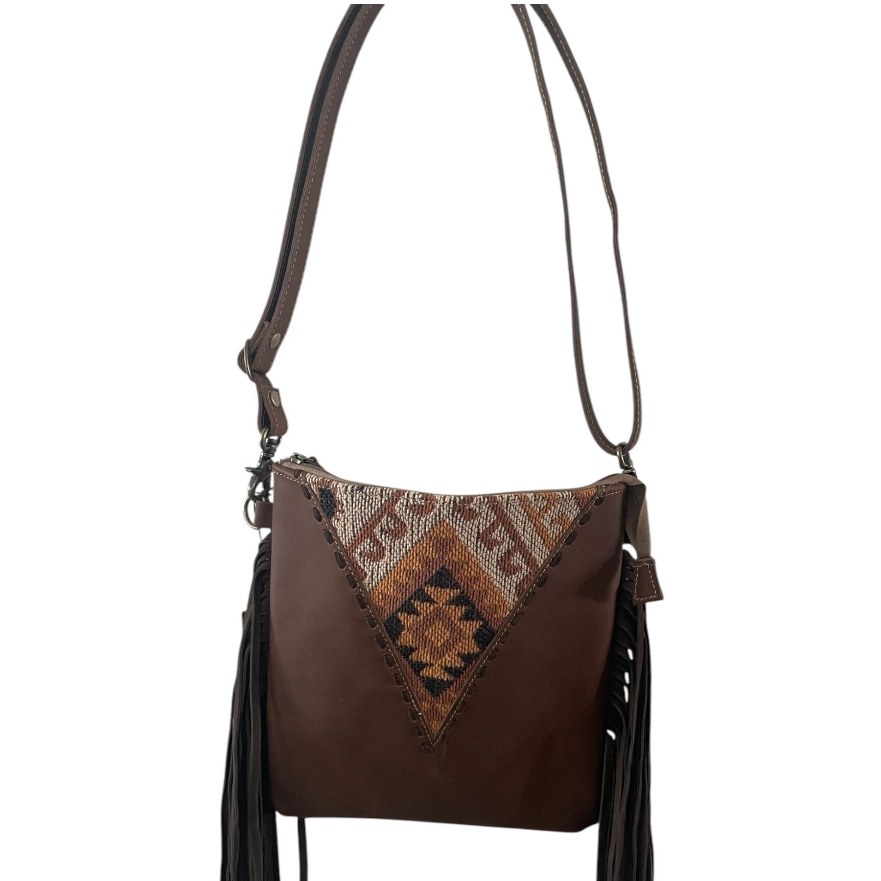 Brown leather handbag with patterned flap and fringes on a white background