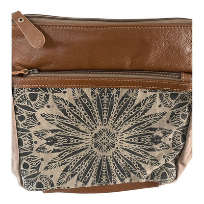 Brown leather crossbody bag with a patterned flap on a white background
