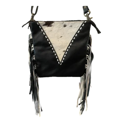 Black leather crossbody bag with white cowhide pattern and fringes on a white background