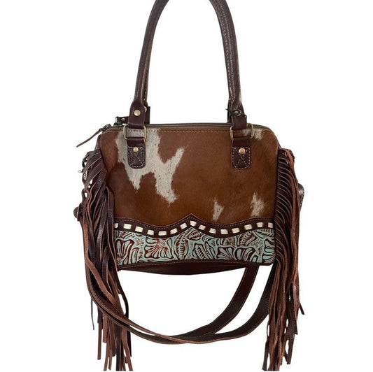 Brown leather handbag with white cowhide pattern and fringes on a white background