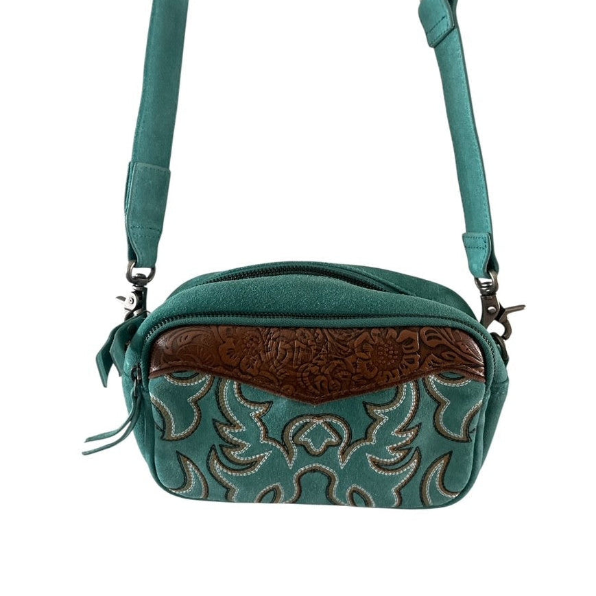 Teal crossbody bag with brown leather patch on a white background