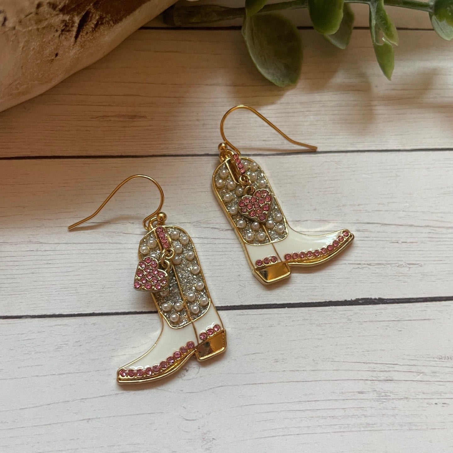 Gold earrings with pink gemstones on a wooden surface