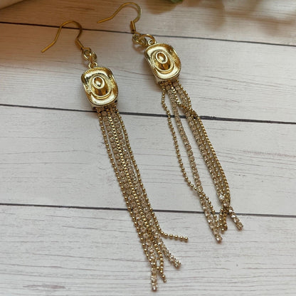 Gold earrings with chain tassels on a wooden surface