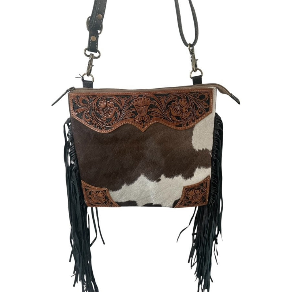 Cowhide leather handbag with fringe and intricate design on a white background