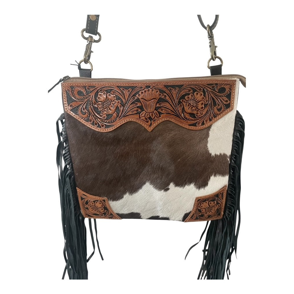 Cowhide leather handbag with intricate tooled design and fringes on a white background