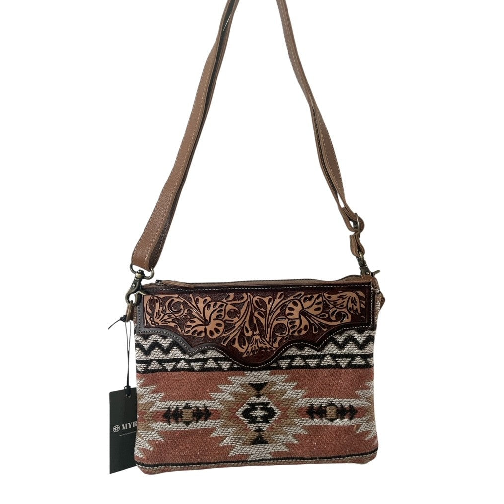 Crossbody bag with patterned design and brown strap on a white background