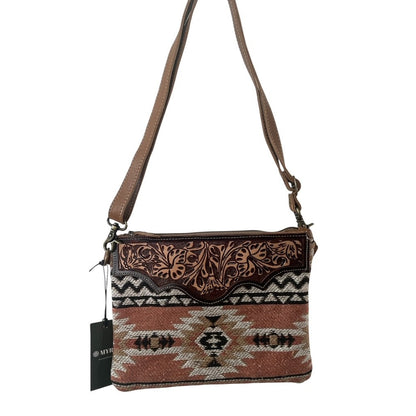 Crossbody bag with patterned design and brown strap on a white background