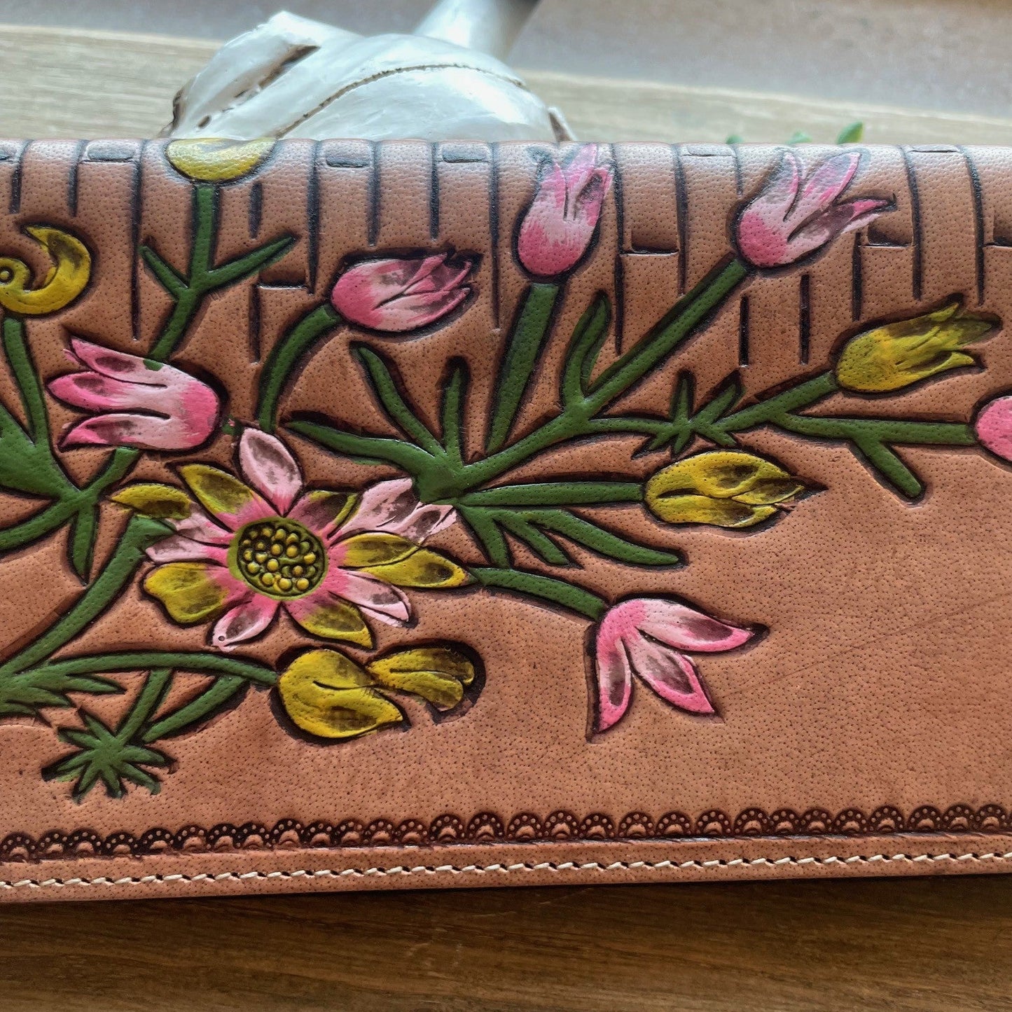 Leather wallet with floral embroidery on a wooden surface