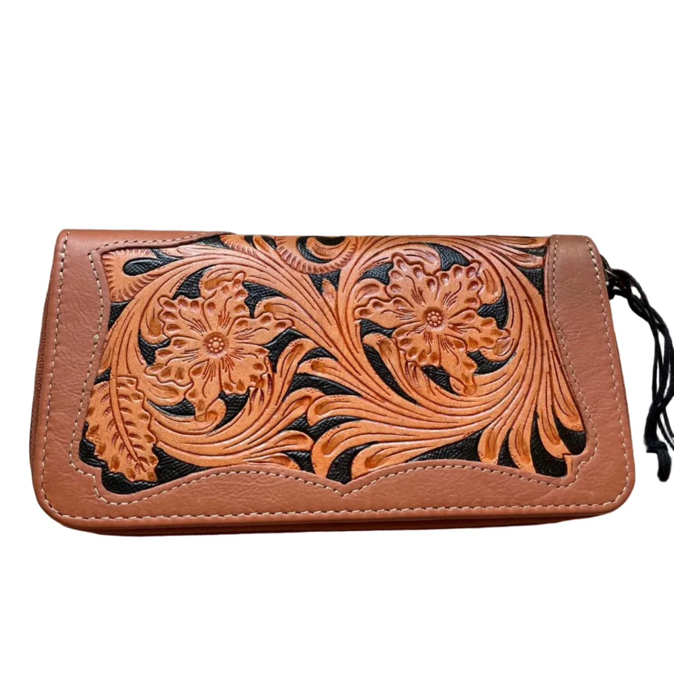 Brown leather wallet with floral tooling on a wooden surface with a skull and plant in the background