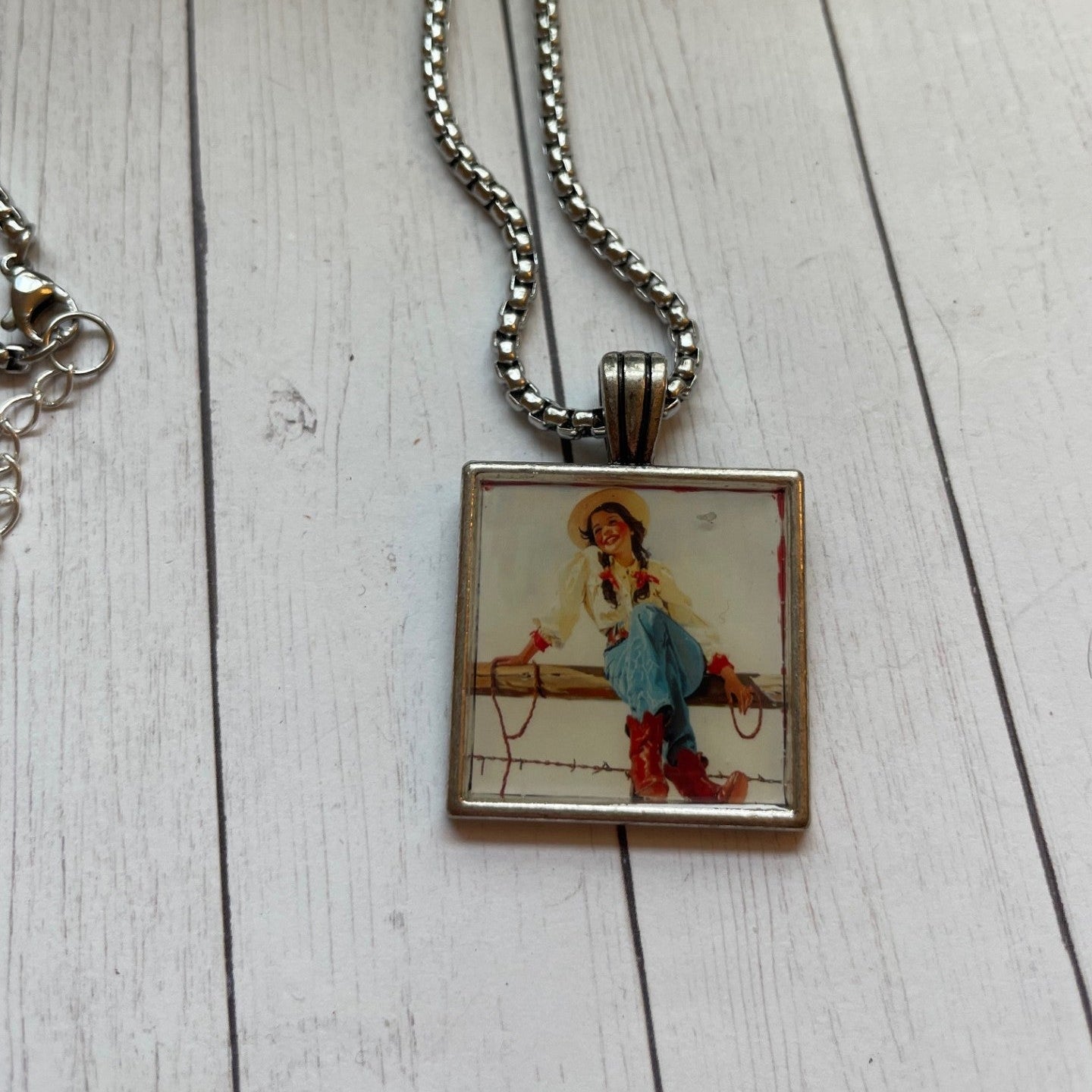 Necklace with a pendant featuring a cowboy illustration on a wooden surface